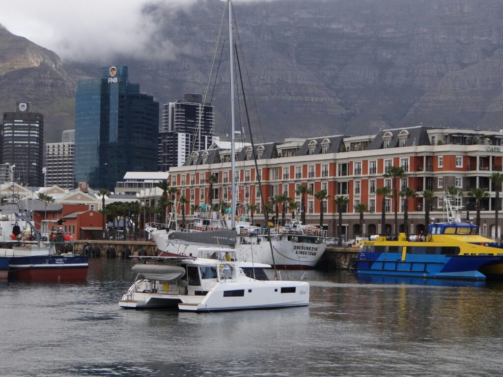 A yacht in a bay on a cloudy day with beautiful buildings in the background
