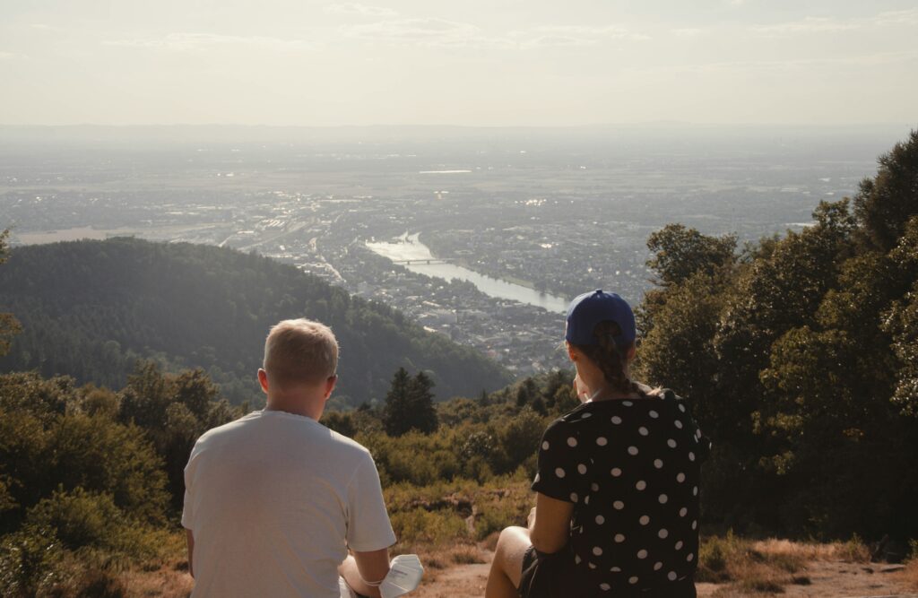 Two people sitting on Königstuhl mountain and looking into the valley at sunset