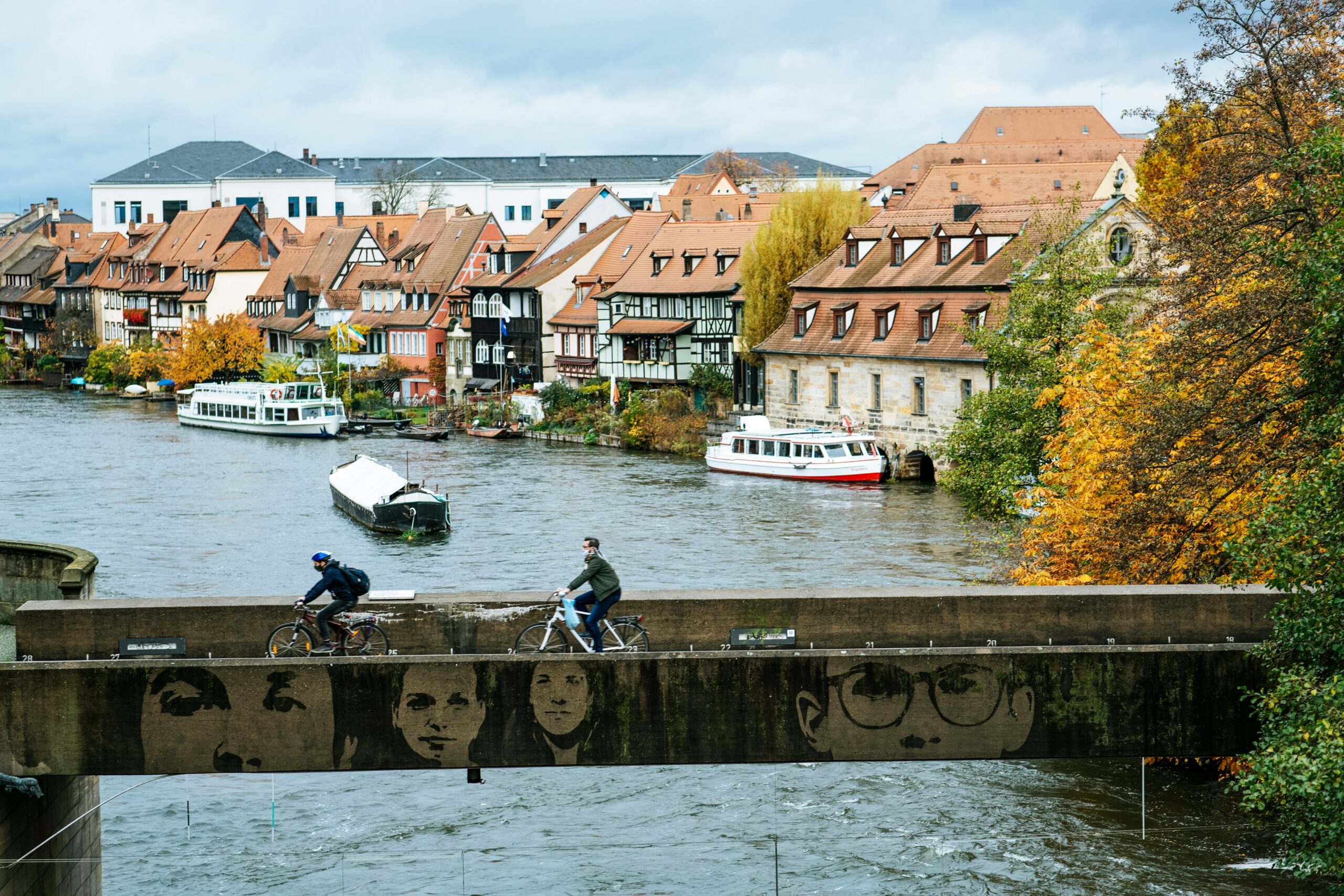 A river and a bridge in Bamberg on which two cyclists are riding