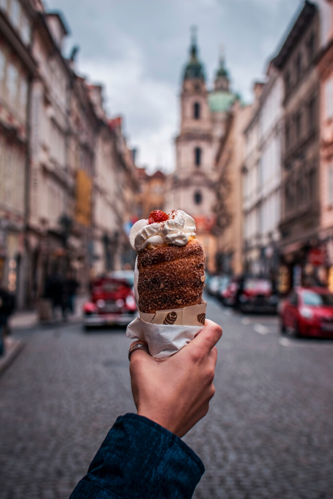 Trdelník in hand of a woman with church in background
